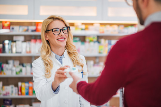 Beautiful Blonde Pharmacist Giving Medicament To A Patient.