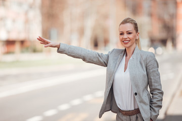 Elegant woman hailing taxi on a sunny day.
