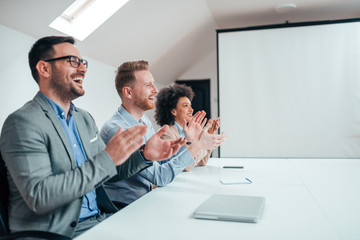 Group of cheerful business people on a presentation applauding.