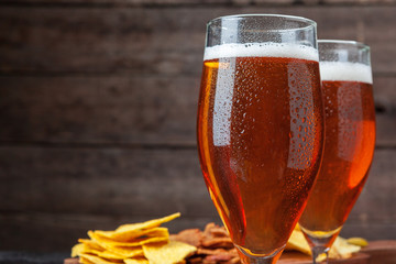 Glass beer and snacks against wooden background