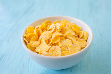 Healthy breakfast. Cornflakes in a white cup, standing against a blue background.