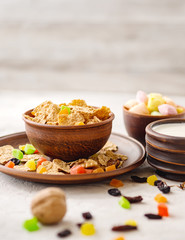 Morning still life. Healthy breakfast (wheat flakes, walnuts, candied fruits, raisins, milk) on a gray textured background