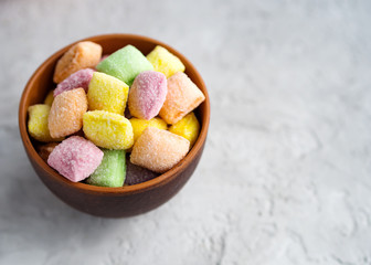 Multicolored sweets (candy pads) in a clay cup , on a blue textured background.