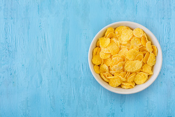 Healthy breakfast. Cornflakes in a white cup, standing against a blue background.