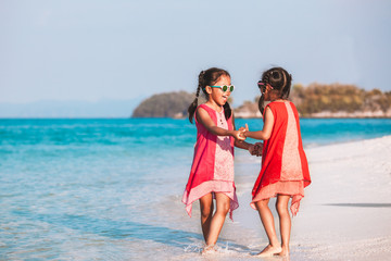 Two cute asian child girls holding hand each other and playing together on beach near the sea in summer vacation