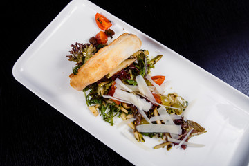 Salad with smoked meat, sausages, cheese, grapes, cherry-tomatoes, olives, basil leaves, arugula and dried tomatoes
