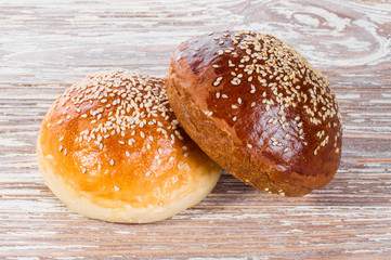 two bun with sesame seeds on wooden background
