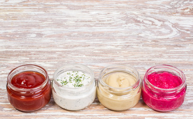 ketchup, mayonnaise, mustard, horseradish on wooden background