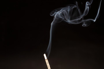 Aromatic stick with blue smoke on a black background. Abstract esoteric empty background with incense.