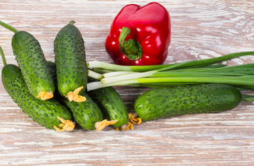 vegetables cucumbers, peppers and onions on wooden background