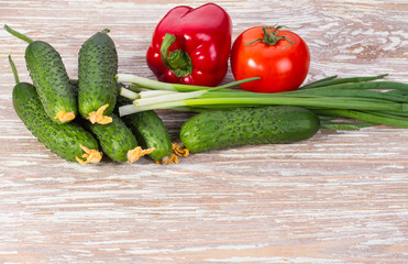 vegetables cucumbers, tomato, pepper and onion on wooden background