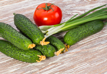 vegetables cucumbers, tomato and onion on wooden background