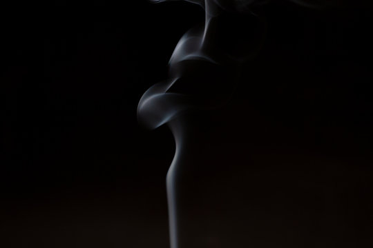 Smoke from aromatherapy incense sticks with the smell of sandalwood and essential oil in Chinese medicine. Abstract smoke in the shape of a female silhouette. Magazine photo format.
