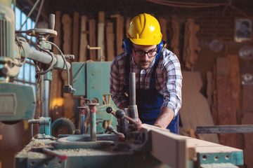 Carpenter cutting a piece of wood in his woodwork workshop
