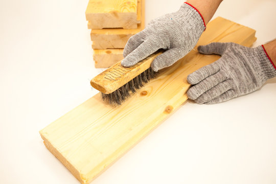 Hand wire brush men's hands in protective gloves on vintage wooden Board. Aging wooden boards by brushing. White background. Create fotofone