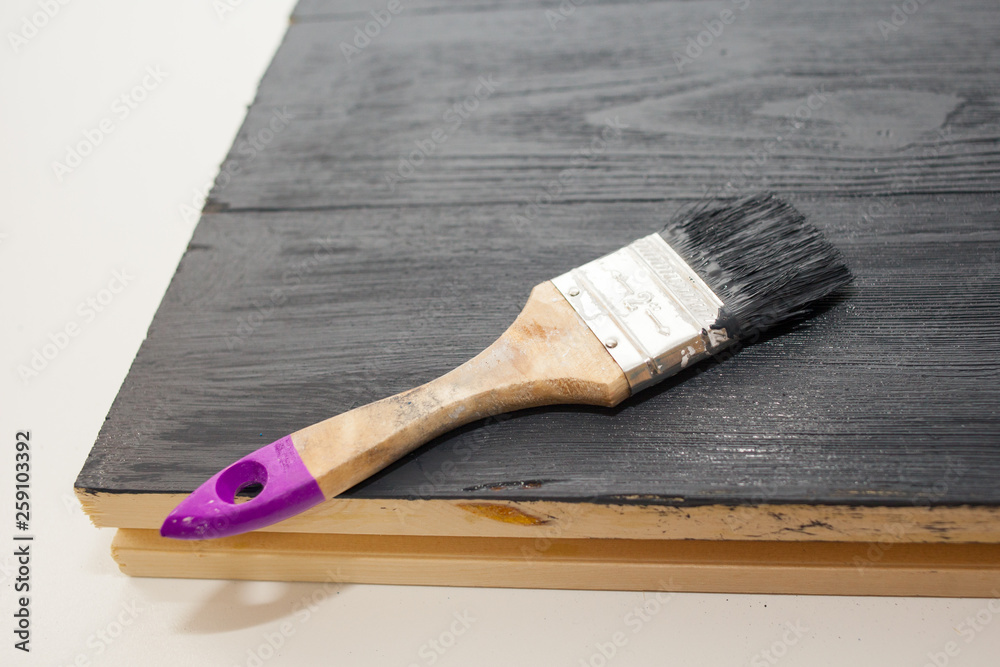 Wall mural painter paints the Board in black. Work in protective gloves. Painting of wooden boards with acrylic paint.