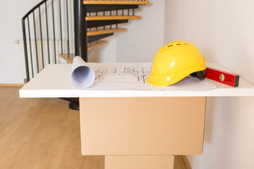Utensilien für den Architekten auf einer Tischplatte: Bauskizze, Helm und Wasserwaage, closeup