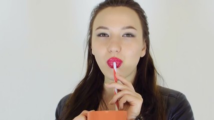 Sexy girl drinking through a straw. The girl has brightly painted lips. She poured her tongue, pierced tongue - Powered by Adobe