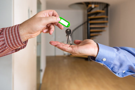 Der Wohnungsschl&uuml;ssel wird &uuml;bergeben, im Hintergrund ist eine leere Maisonette Wohnung zu sehen