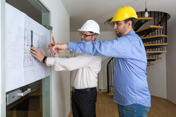 Bauherr und Architekt diskutieren Details des Bauplans und zeichnen Veränderungen ein