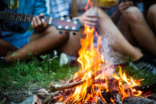 Friends playing music and enjoying bonfire in nature