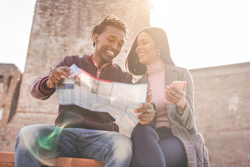 Black couple looking city map app during vacation tour