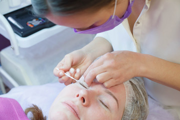 Obraz na płótnie Canvas Woman on the procedure for eyelash extensions, eyelashes lamination