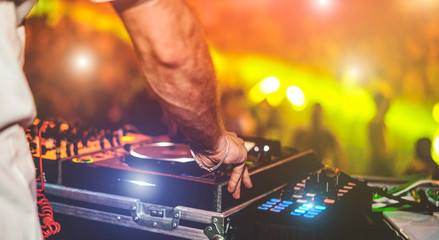 Dj mixing outdoor at beach party festival with crowd of people in background - Soft focus on hand