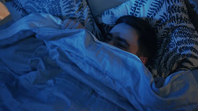 Guy laying in bed, covering slowly blanket. Time for sleeping. Young man falling asleep. Home. Comfort, coziness, bedroom, bedtime, disturbed, exhausted, frustrated, human, lifestyle, peace