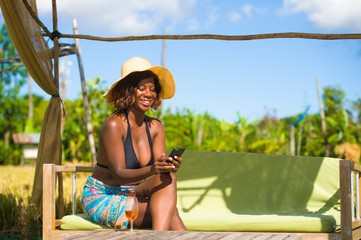 young happy and attractive black afro American woman in bikini using internet social media on...