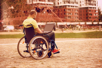 man on wheelchair working on laptop