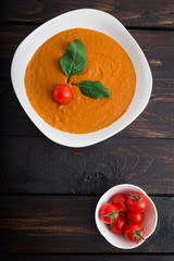 Pumpkin and carrot cream soup with  parsley in  a white bowl on dark wooden background. Rustic, food.