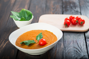 Pumpkin and carrot cream soup with  parsley in  a white bowl on dark wooden background. Rustic, food.