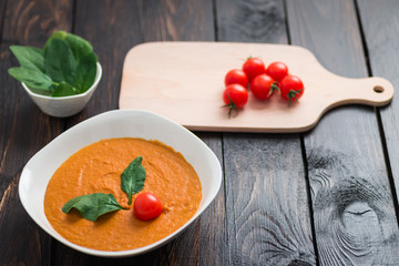 Pumpkin and carrot cream soup with  parsley in  a white bowl on dark wooden background. Rustic, food.