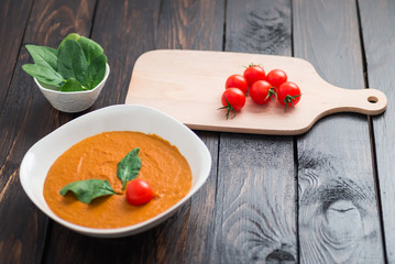Pumpkin and carrot cream soup with  parsley in  a white bowl on dark wooden background. Rustic, food.