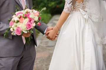 Elegant wedding couple. Bride and groom holding hands at wedding day
