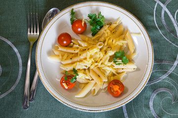 Delicious penne  pasta with cherry tomatoes and cheese on white plate.