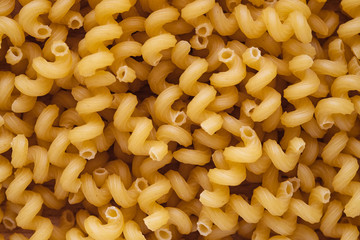 Top view of spiralli dry Italian pasta. Yellow uncooked macaroni texture for background.