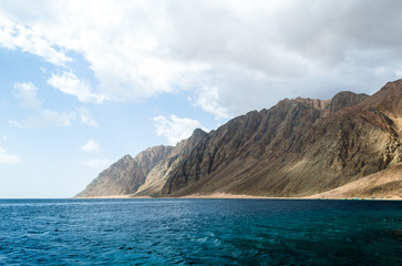 blue sea and high rocky mountains against the sky and clouds in Egypt Dahab South Sinai