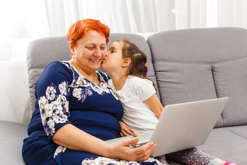 Grandmother Using Laptop And Calculator With Granddaughter
