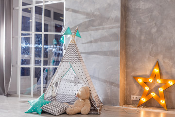 Stylish modern children room. Kid's wigwam in children room. Large wooden star lamp. Interior scandinavian style. © Angelov