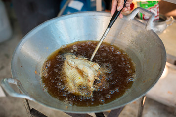 Chef cooking deep-fried fish in the big pan to Chinese banquet food preparation. fat from trans-fat concept. disease from cholesterol and Trans-fatty concept. image for copy space and objects.