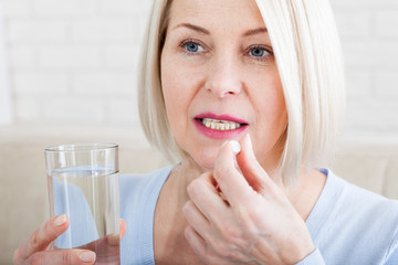 medicine, health care and people concept, close up of middle aged woman taking in pill