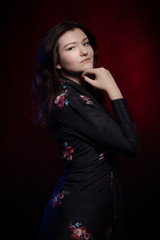 Brunette actress girl in black dress posing on a dark background in blue and red light.  