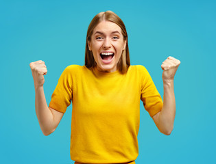 Excited girl with widely open mouth holds hands clenched in fists, exclaimed with positiveness....