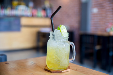Lemon juice with honey on wooden table. Lemon fizz in a glass. Honey and lemon soda of drink summer. Honey lemon drink on the cafe table .