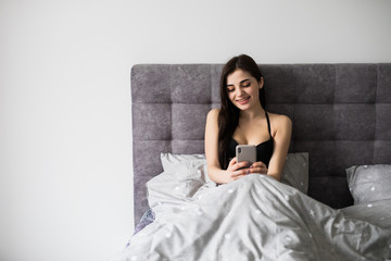 Young woman wake up and take phone in hand to check social networks in the morning, Phone addiction.