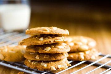 Peanut cookies on cooling rack with milk on wooden table