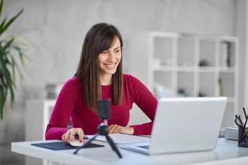 Beautiful smiling Caucasian businesswoman sitting in modern office and using laptop.