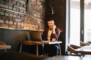 Young handsome man sitting in office with cup of coffee and working on project connected with...